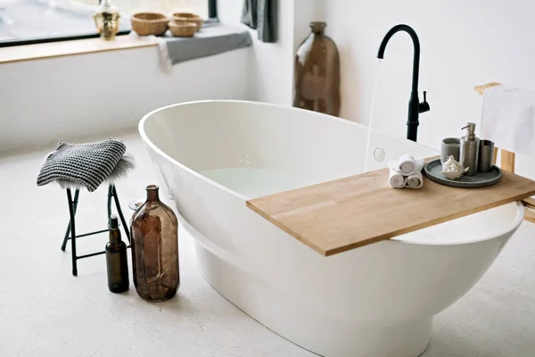 Modern bir dairede köpük suyla dolu beyaz bir küvet. Şık bir iç dekorasyon, ev dekorasyonu. Spa konsepti, rahatlama. Yumuşak seçici odak.