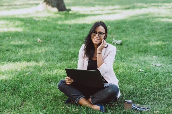 女商人坐在夏天的草地公园里使用笔记本电脑 一个商人在检疫期间工作得很远 软性选择性重点 — 图库照片