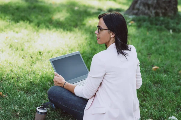 年轻妇女在室外工作时使用带有空白屏幕的笔记本电脑 大流行病期间的远程学习和远程工作 软性选择性重点 — 图库照片