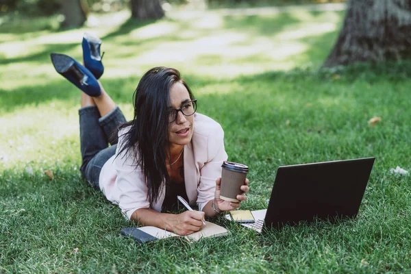 Bizneswoman Leży Letnim Parku Trawiastym Używając Laptopa Szklanką Kawy Ręku — Zdjęcie stockowe