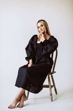 Siyah keten elbiseli güzel sarışın kadın. Etnik moda, doğal kumaş. Yumuşak seçici odak.