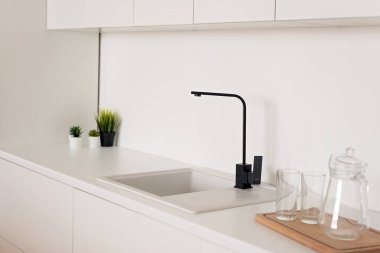 Beyaz mutfak lavabosundaki modern siyah musluk. Yumuşak seçici odak.