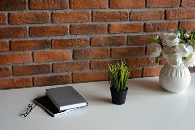 Yaratıcı bir işyeri çatı katı duvarı ve beyaz masa üzerinde aksesuar. Boşluğu kopyala, yumuşak seçici odak.