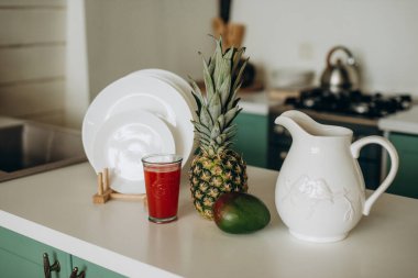 Sağlıklı kahvaltı, bir bardak taze greyfurt, mango, ananas beyazı sofra takımı. Yumuşak seçici odak.