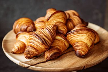 Taze pişmiş kruvasan. Sıcak kokulu kruvasanlar ve ahşap bir stantta yuvarlanmalar. Fransız ve Amerikan hamur işleri tüm dünyada popülerdir..