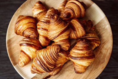 Taze pişmiş kruvasan. Sıcak kokulu kruvasanlar ve ahşap bir stantta yuvarlanmalar. Fransız ve Amerikan hamur işleri tüm dünyada popülerdir..