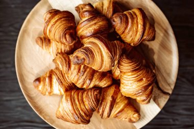 Taze pişmiş kruvasan. Sıcak kokulu kruvasanlar ve ahşap bir stantta yuvarlanmalar. Fransız ve Amerikan hamur işleri tüm dünyada popülerdir..