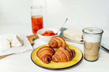 Taze kruvasanla kahvaltı ve bir fincan aromatik kahve latte, mandalina reçeli, tereyağı ve peynir. Sağlıklı kahvaltı..