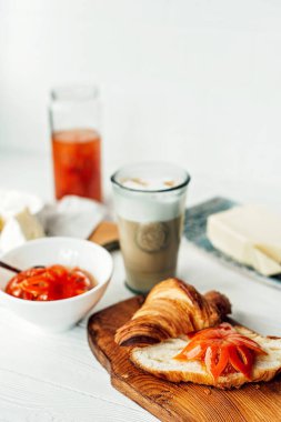 Taze kruvasanla kahvaltı ve bir fincan aromatik kahve latte, mandalina reçeli, tereyağı ve peynir. Meyve oymacılığı. Sağlıklı kahvaltı..