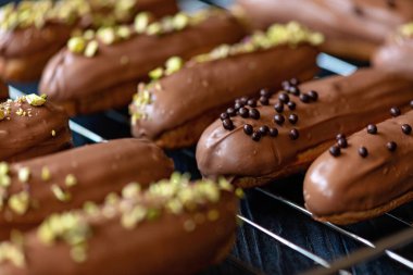 Fransız tatlı eklerleri ya da sütlü çikolata jöleli profiteroller, bir fırın rafında damla ve şam fıstığı. Kremalı ve soslu hamur tatlısı. Yumuşak seçici odak.