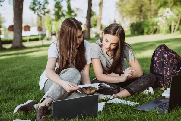 Dwie Studentki Siedzą Parku Trawie Książkami Laptopami Ucząc Się Przygotowując — Zdjęcie stockowe