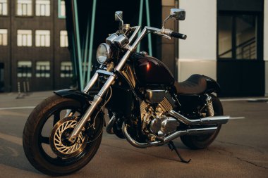Gün batımının sıcacık ışığında otoparkta bir motosiklet. Özel yapım krom detaylı motosiklet. Yumuşak seçici odak.