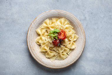 Seramik tabakta açık beton zemin üzerinde Farfalle makarna, yukarıdan görüş.