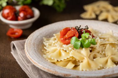 Tahta zemin üzerinde seramik bir tabakta Farfalle makarna, seçici bir odak