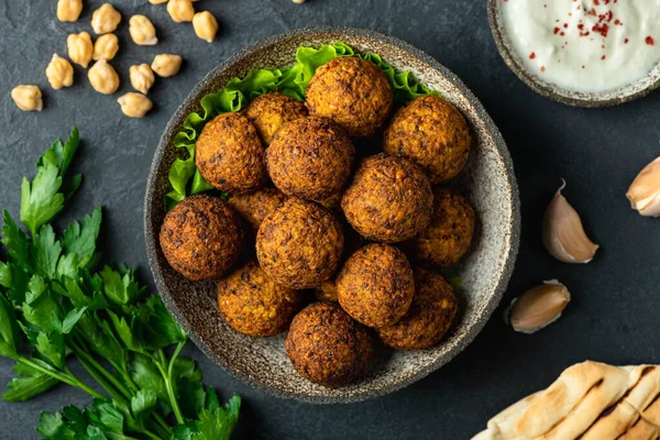 Siyah arka planda seramik bir kasede falafel topları.