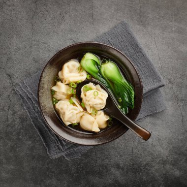 Çin wonton çorbası siyah seramik kasede, yukarıdan görünüyor.
