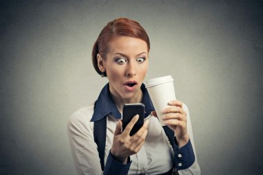 surprised business woman reading news on smart phone drinking soda coffee 