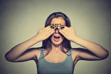Young woman with eyes painted on her hands isolated on gray wall background 