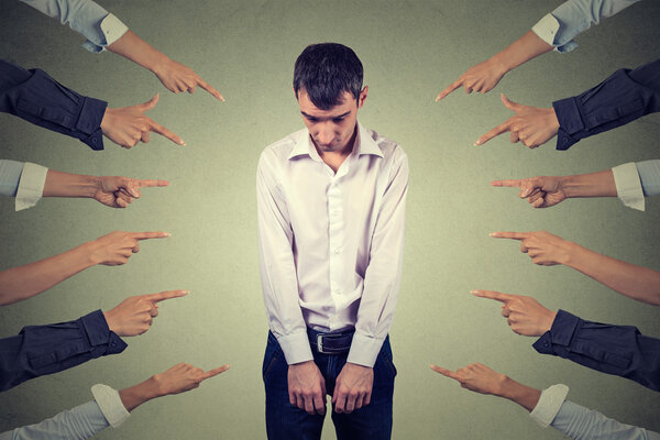 Обвинение в виновности. Грустный расстроенный человек смотрит вниз много пальцев указывая на него
