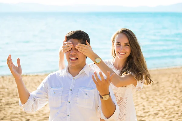 Beautiful woman covering eyes of boyfriend smiling while both standing outdoors — Stok fotoğraf