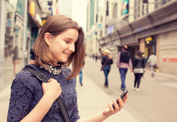 Felice ragazza a piedi e sms sul telefono intelligente in strada — Foto Stock