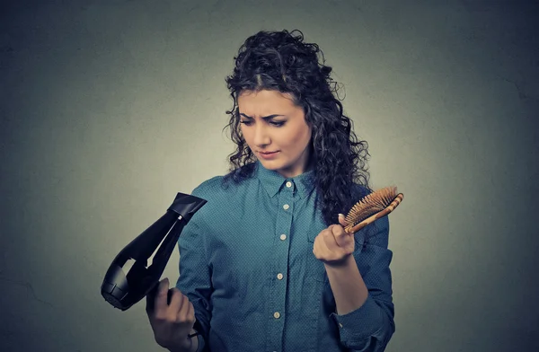 Upset young woman with hair dryer and hair brush — Stok fotoğraf