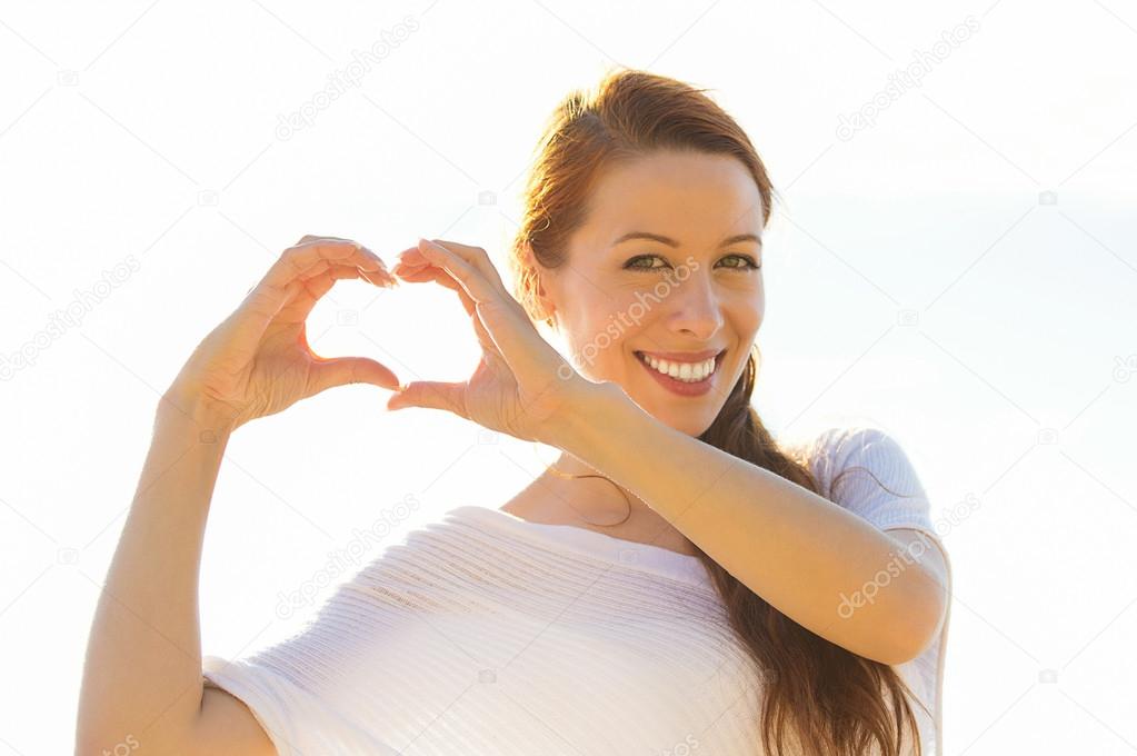 smiling happy young woman making heart sign