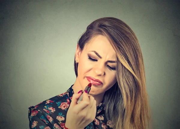 Mujer molesta disgustada aplicando lápiz labial —  Fotos de Stock