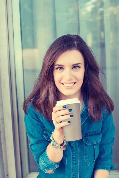 Mujer sonriente bebiendo café al aire libre sosteniendo una taza de papel — Foto de Stock