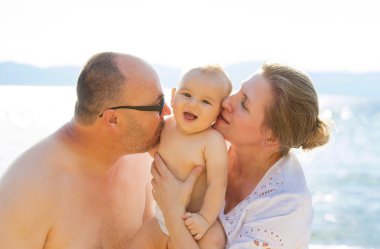 Grandchild and grandparents having fun outdoors on summer sunny day by the beach