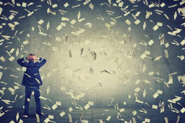 business man standing in front of wall under money rain dollar banknotes falling down clipart