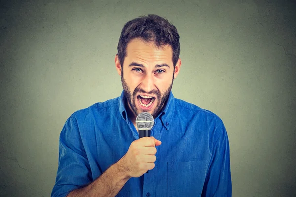 Closeup retrato frustrado homem com microfone isolado no fundo da parede cinza — Fotografia de Stock