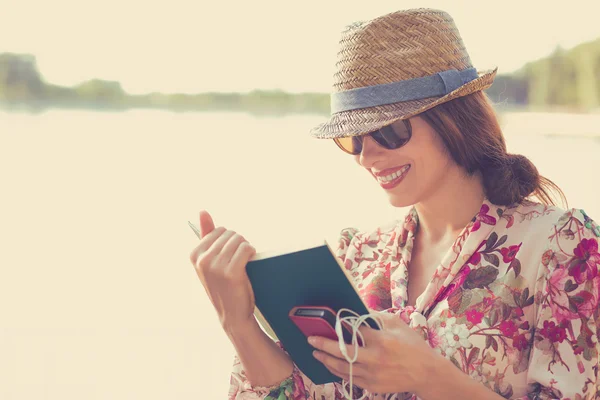 Young woman sitting outdoors and reading a book — Stock Photo, Image