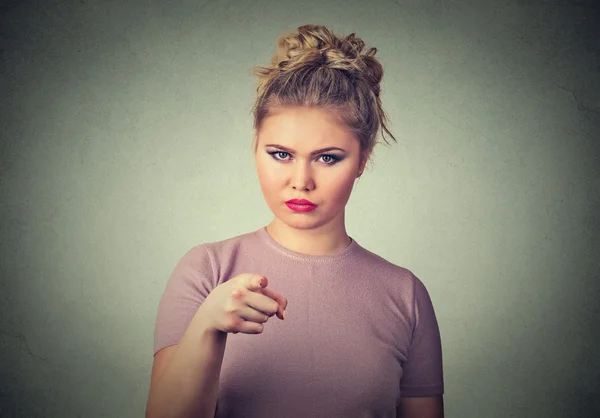 Angry young woman pointing at camera isolated on grey wall background — Stock Photo, Image