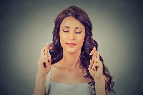 Young woman crossing her fingers, eyes closed, hoping wishing — Stok fotoğraf