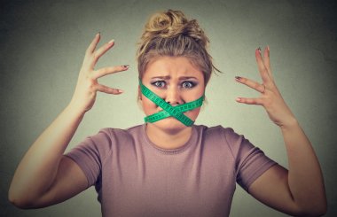 Frustrated woman with measuring tape around her mouth. Diet restriction and stress clipart