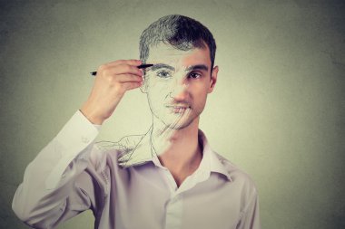 Young man drawing self portrait face, hiding true emotion. Private life, identity concept