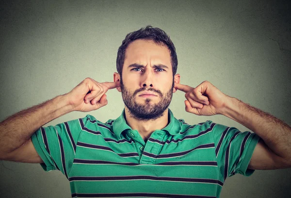 Headshot displeased young man plugging ears with fingers doesn't want to listen — Stock Photo, Image