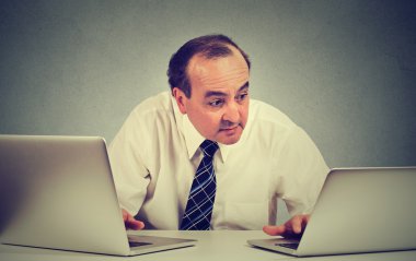 Orta yaşlı iş adamı ofisinde iki bilgisayar üzerinde çalışan multitasking 