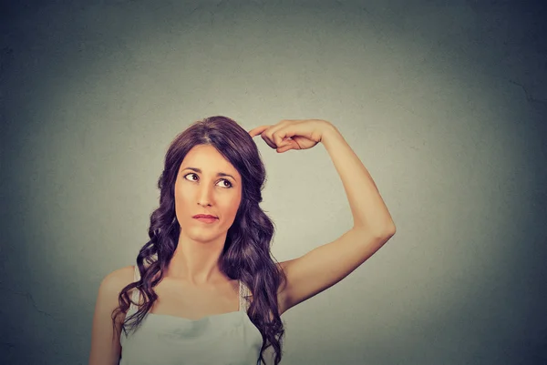 Young woman scratching head, thinking daydreaming deeply about something looking up Stockbild