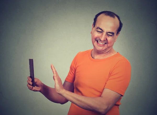 Diyet adamı. Kafası karışmış adam dayanmaya çalışıyor, chocolat yemek için ayartma karşı — Stok fotoğraf