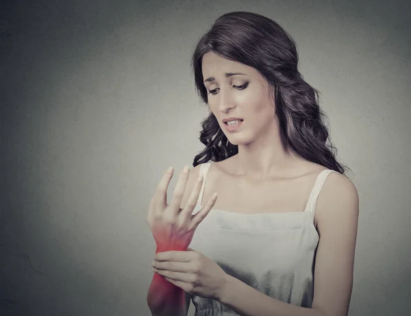 Young woman holding her painful wrist. Negative face expression — Stok fotoğraf