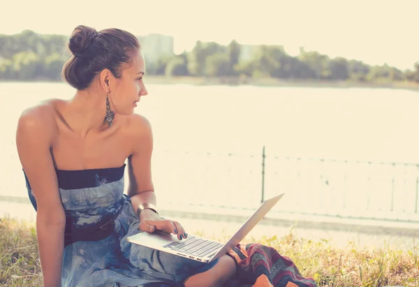 Chica con portátil. Hermosa joven con cuaderno sentado en la hierba —  Fotos de Stock