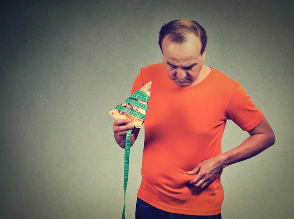 Hombre de mediana edad con rebanada de cinta métrica de pizza y abdomen con sobrepeso . — Foto de Stock