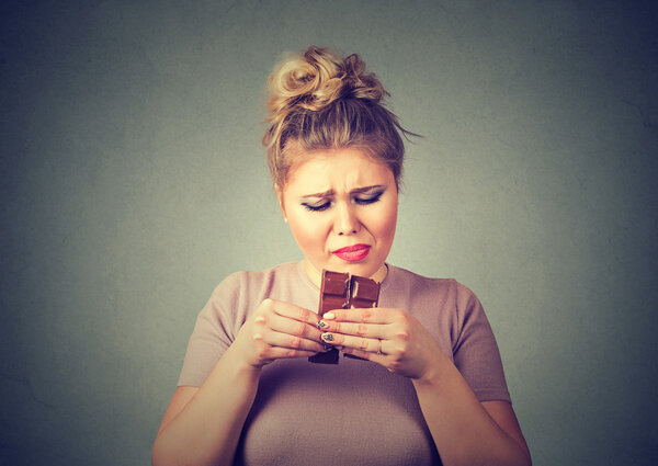 молодая женщина устала от диеты ограничения тягу конфеты шоколад
 