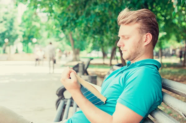 Yaz güneşli günde bir parkta kitap okurken erkek — Stok fotoğraf