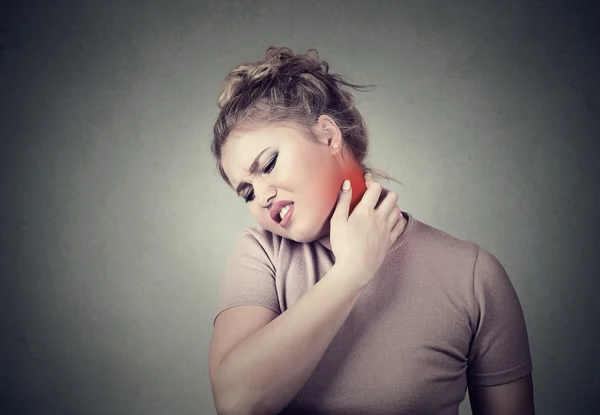 Young woman massaging her painful neck colored in red — Stock Photo, Image