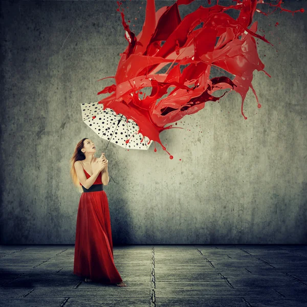 Hermosa mujer en vestido usando un paraguas como refugio contra las gotas rojas pintura cayendo — Foto de Stock