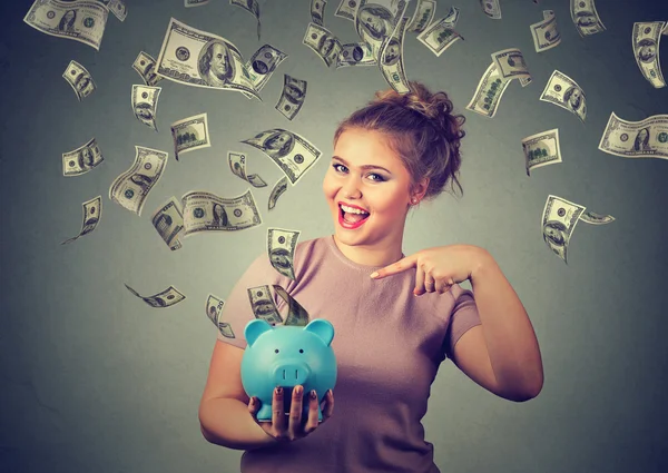 Mulher feliz com o banco porquinho celebra o sucesso sob o dinheiro chuva caindo notas de dólar — Fotografia de Stock