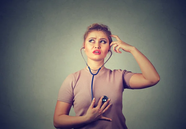 Задумчивая женщина слушает свое сердце стетоскопом — стоковое фото